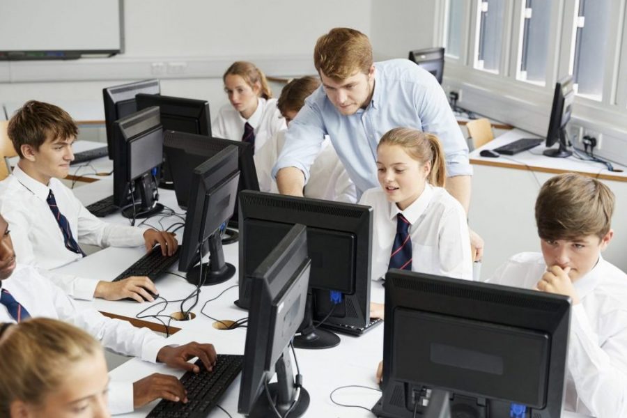 Teenage Students Wearing Uniform Studying In IT Class Teenage Students Wearing Uniform Studying In IT Class