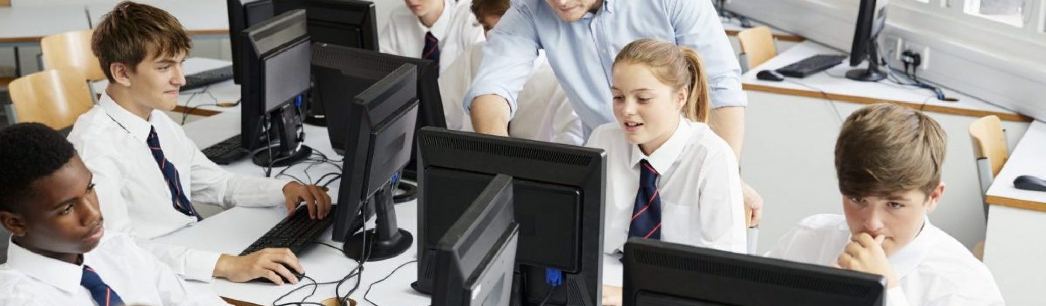 Teenage Students Wearing Uniform Studying In IT Class Teenage Students Wearing Uniform Studying In IT Class