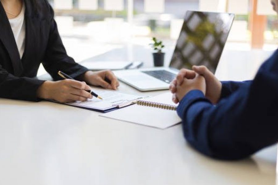 The manager is reading the resume and is interviewing the new employee. Negotiating business and signing a contract. Lawyer and legal advisor.