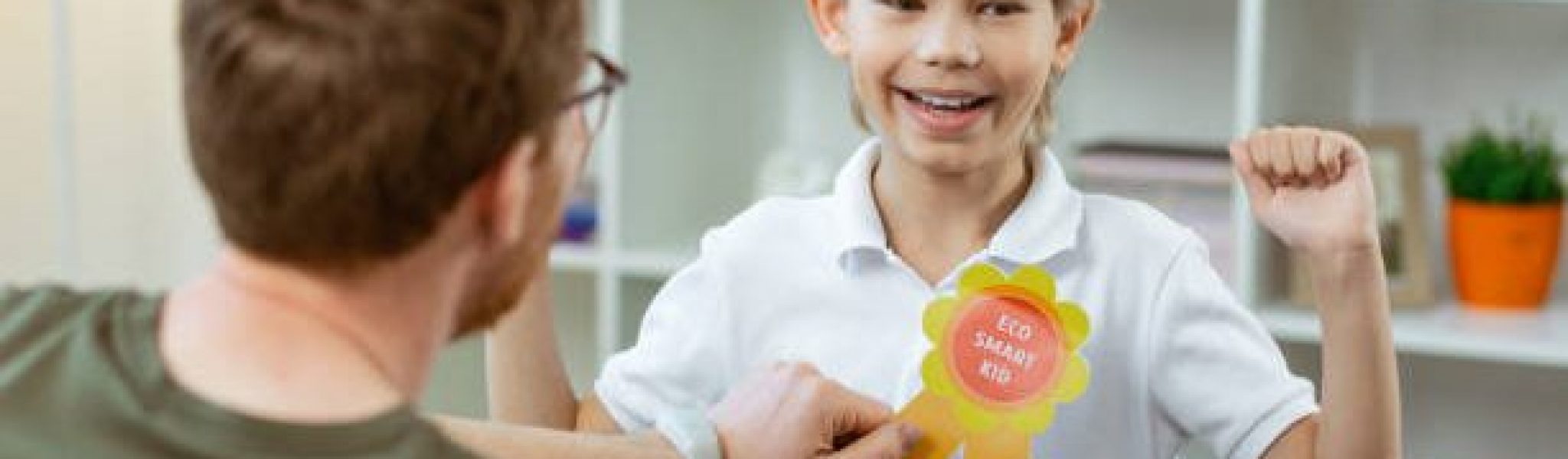Bright rewarding sign. Contented proud boy being happy with his reward from pleasant elementary school teacher