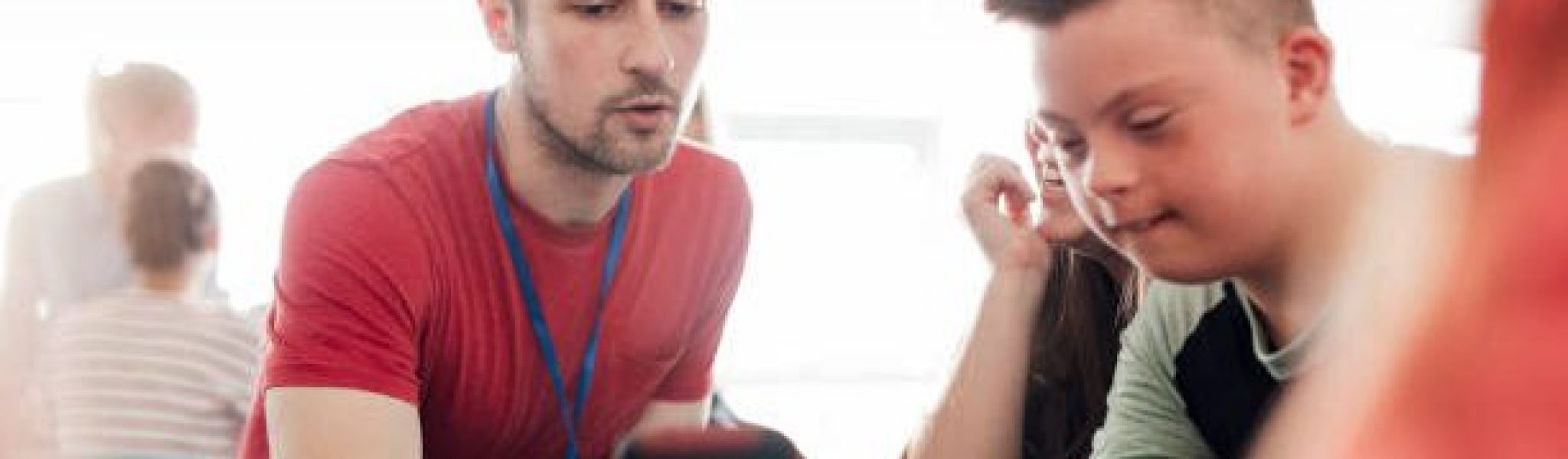 Point of view angle of teacher assisting down syndrome boy with using the smart phone.